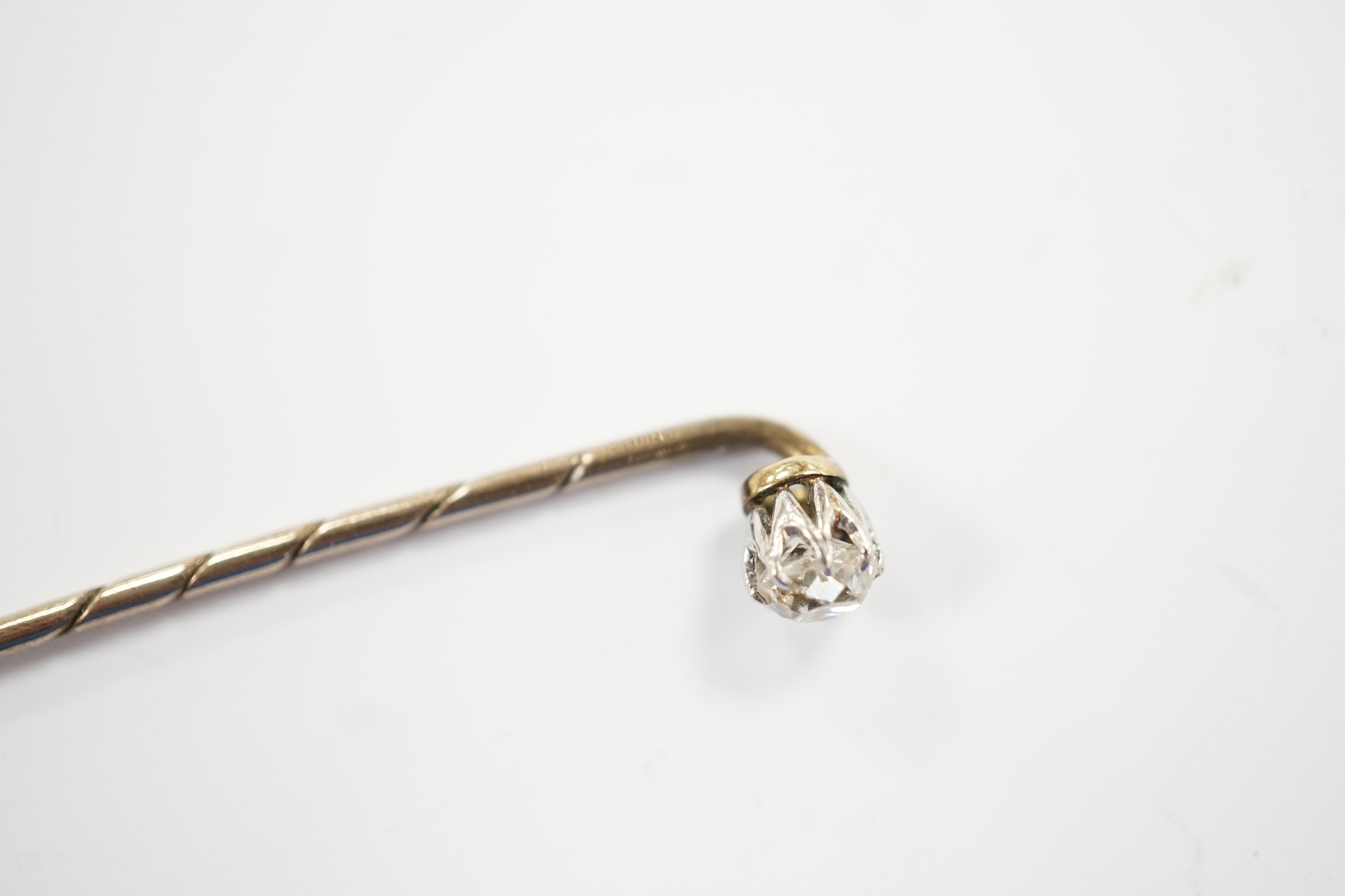 An early 20th century cased yellow metal and cushion cut solitaire diamond set stick pin, 57mm, gross weight 1.3 grams.